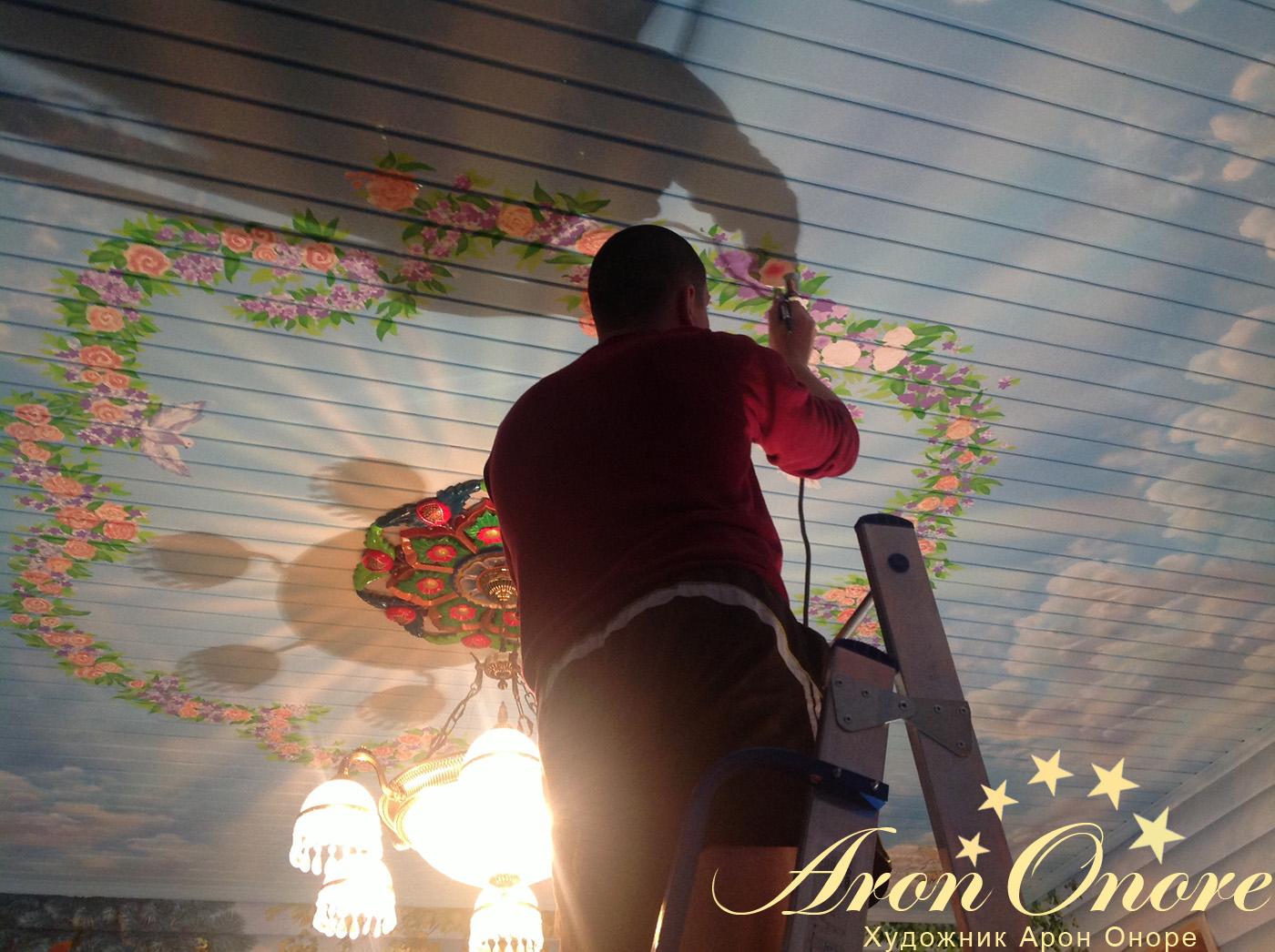 Художник – аэрограф рисует цветы на потолке