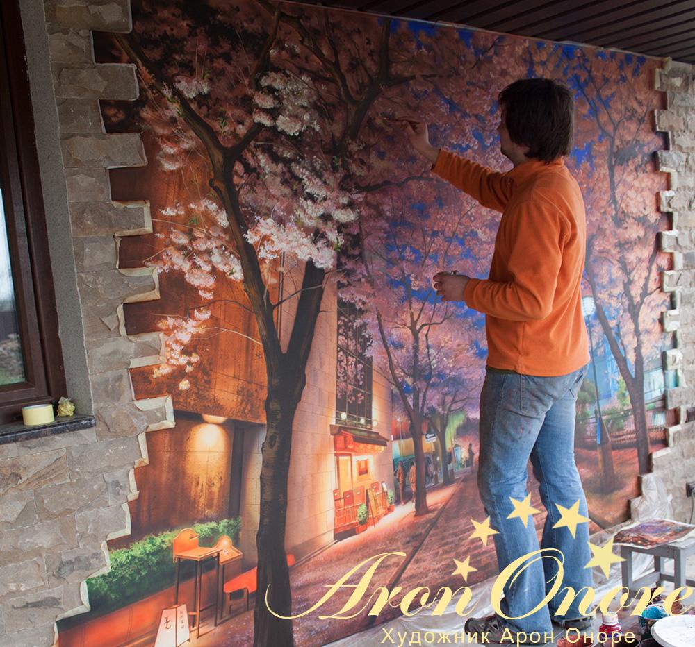 Художник вырисовывает листья на фасаде дома