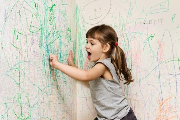 Девочка рисует на стене. 
