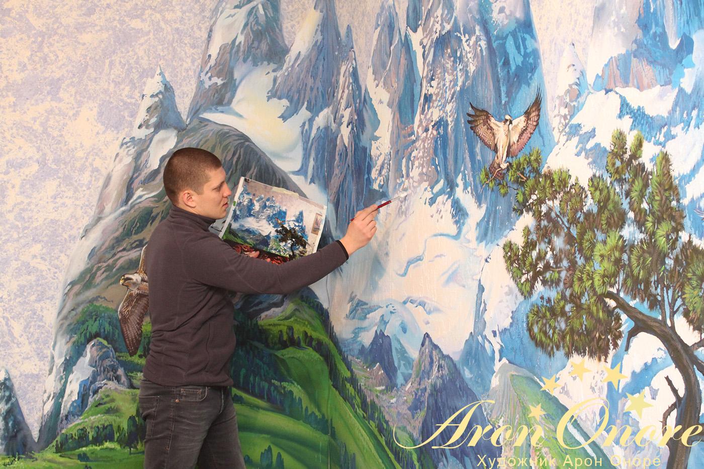 Художник аэрограф – Арон Оноре создает рисунок на стене на тему «Горный пейзаж»