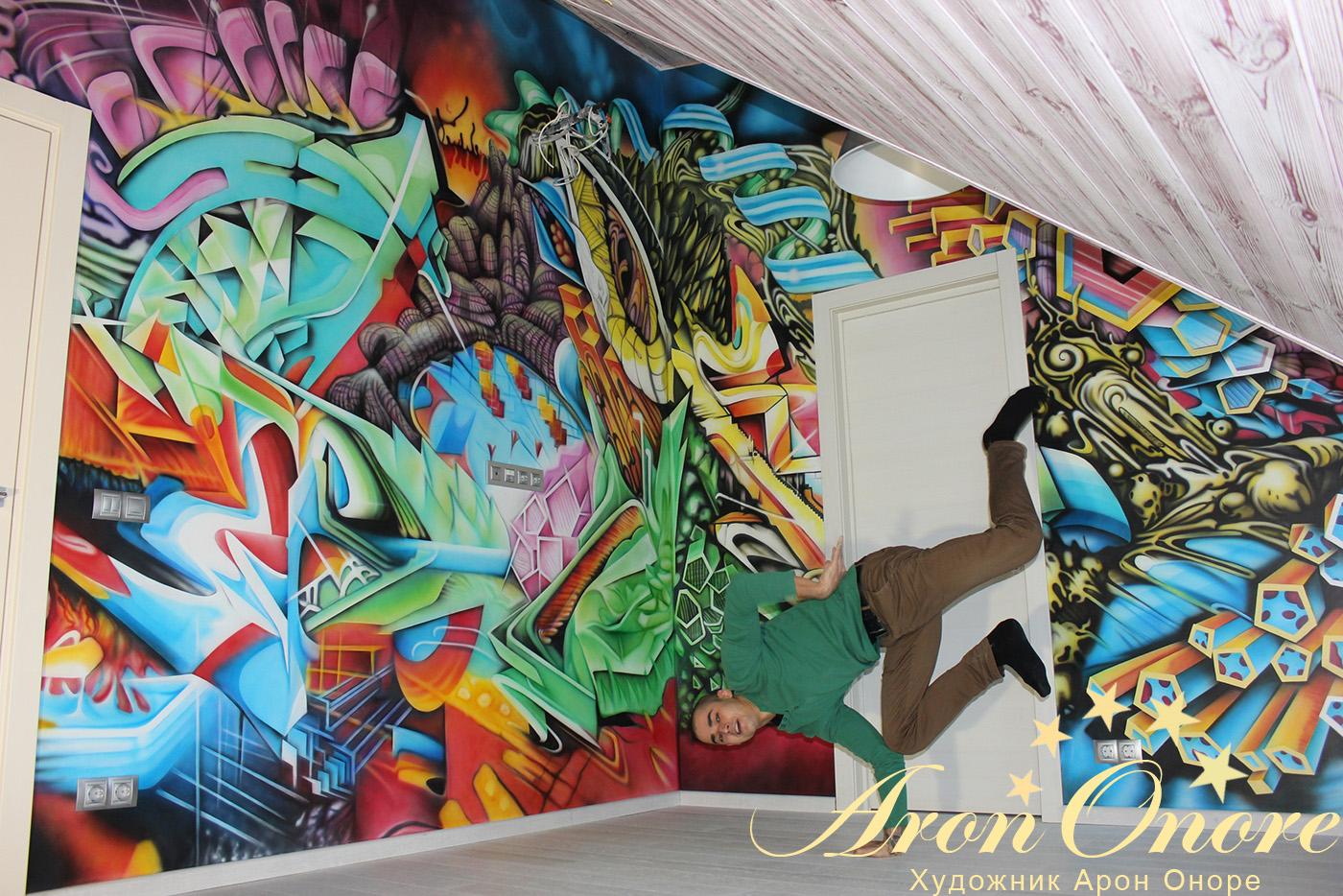 Художник студии аэрографии Арон Оноре на фоне готового граффити на стене