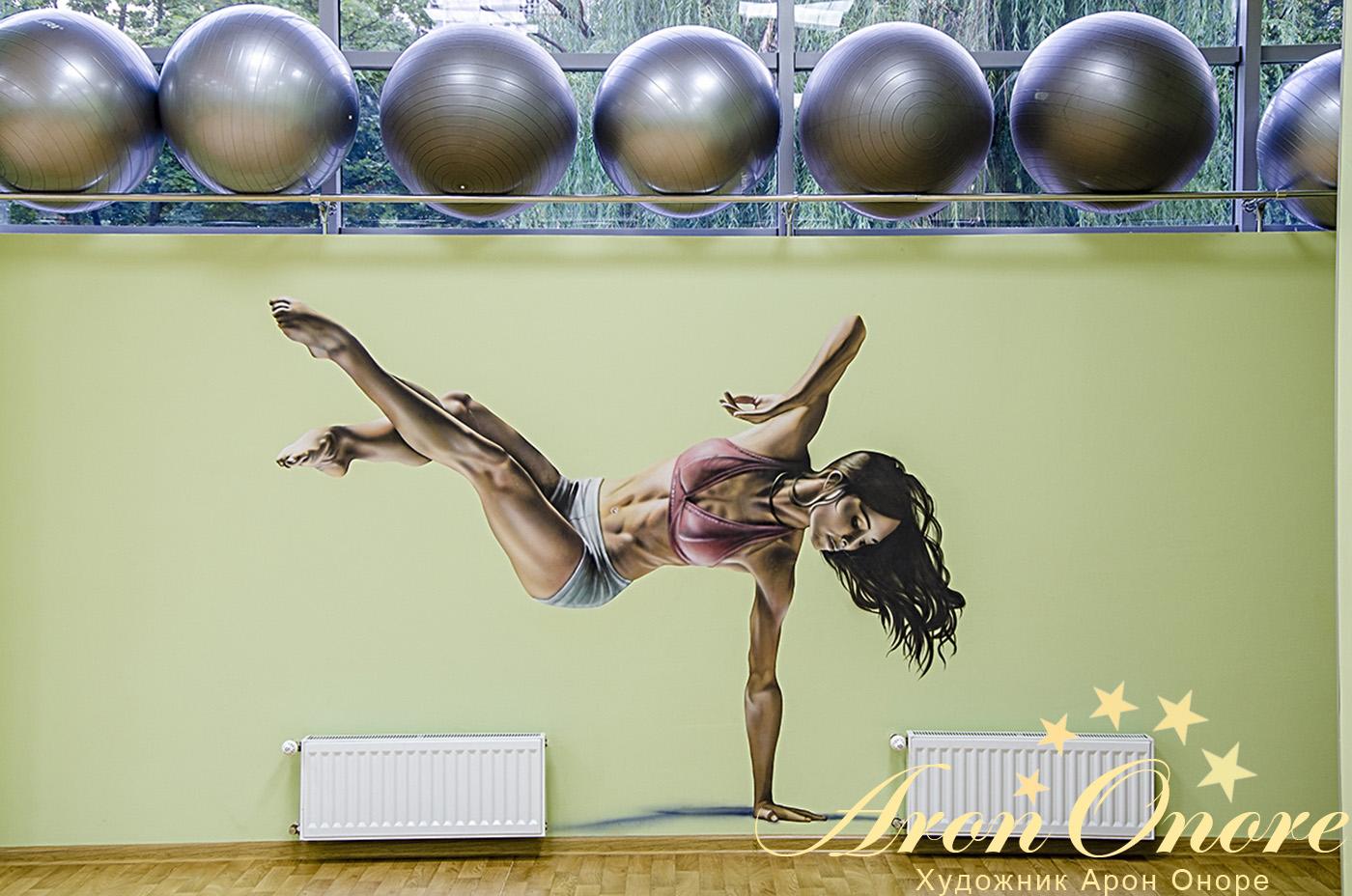 Рисунок на стене спортивного клуба - девушка стоит на руке