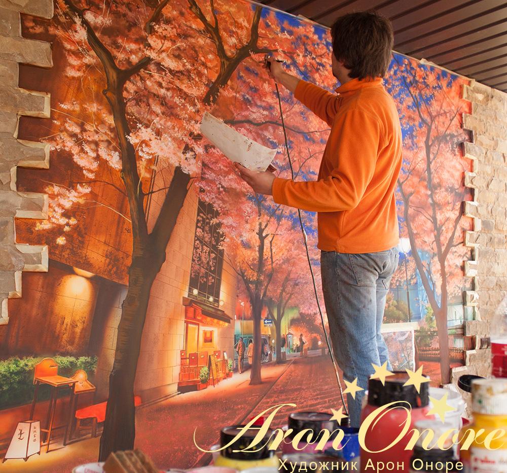 Художник рисует осенние листья на деревьях (рисунок на стене)